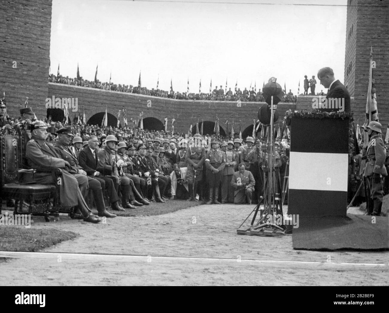 Speech of Chancellor Adolf Hitler at the inauguration of the Tannenberg Memorial in 1933 near Hohenstein, East Prussia (today Osztynek, Poland). In the first row sit (from left) Reich President Paul von Hindenburg, Hermann Goering, Vice-Chancellor Franz von Papen and Reichswehr Minister Werner von Blomberg. In the middle of the picture, left beside a kneeling photographer, Heinrich Hoffmann. Stock Photo