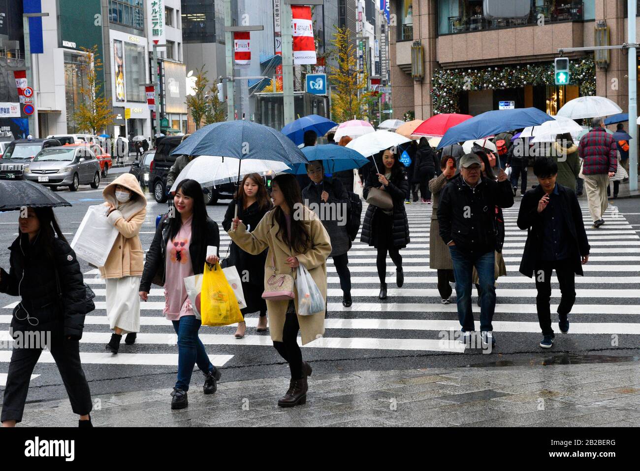 Pedestrians with umbrellas crossing street in the Ginza district of