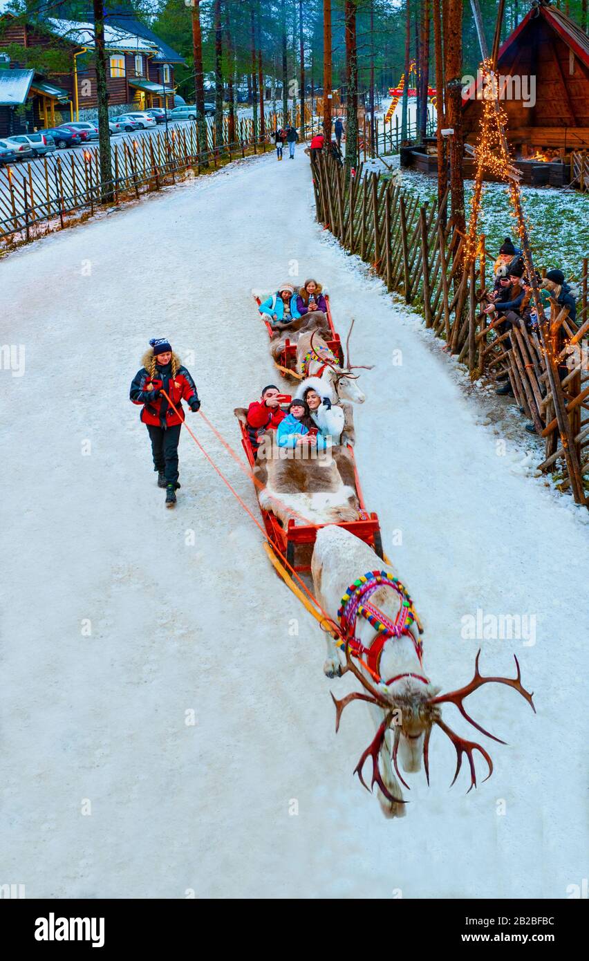 Rovaniemi, Finland, Tourists on reindeer-drawn sledges in the Santa Claus Village and Park Stock Photo