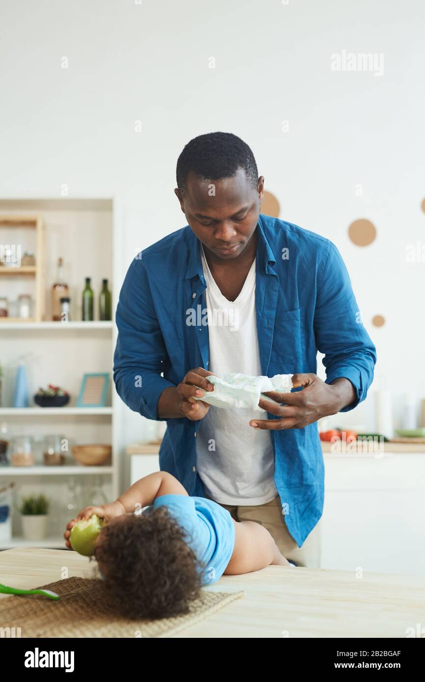 Vertical portrait of adult African-American man changing diaper while  caring for toddler at home, copy space Stock Photo - Alamy