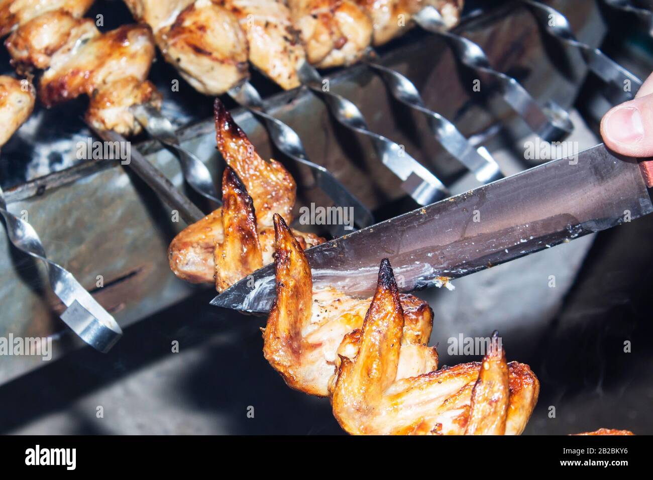 Grilling marinated shashlik preparing on a barbecue grill over charcoal.  Shashlik is a form of Shish kebab popular in Eastern Europe. Shashlyk (meaning  skewered meat) was originally made of lamb. Stock Photo