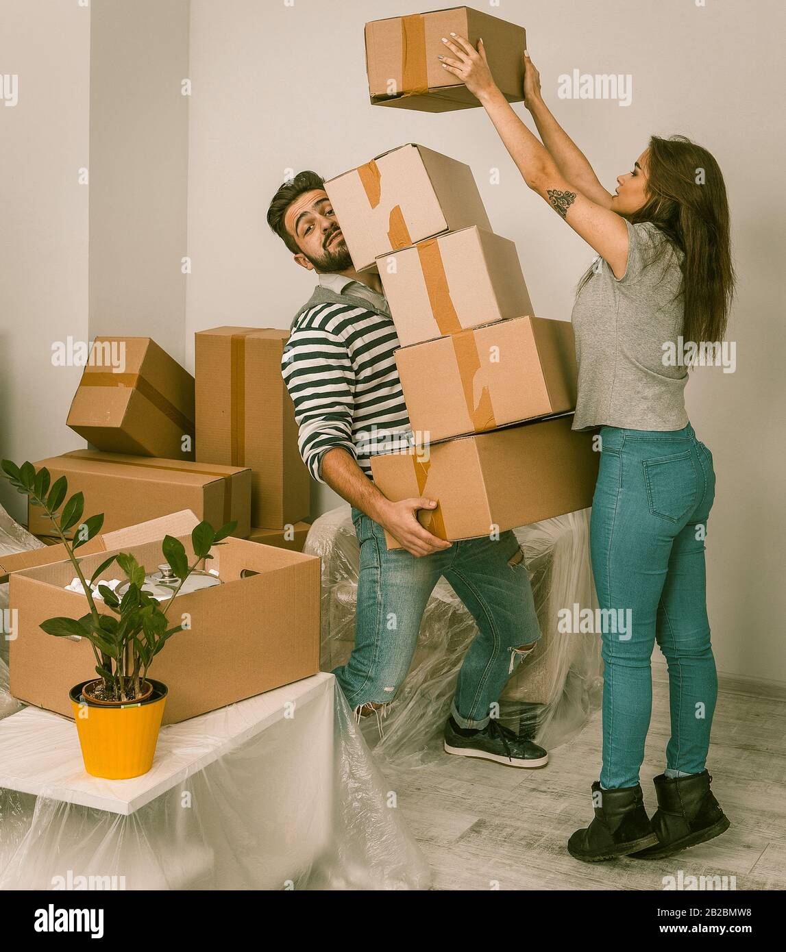 Young man and woman moving in new home, holding lots of carton boxes ...