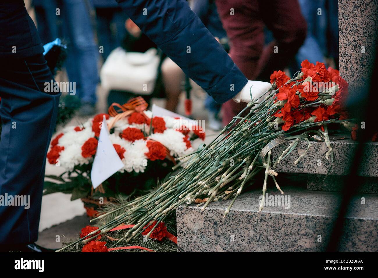 laying flowers at the monument, a soldier in white gloves puts flowers
