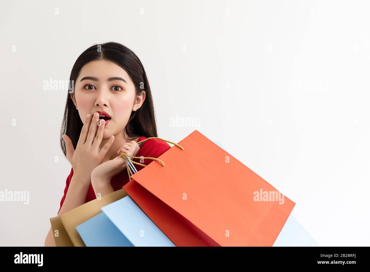 Portrait of asian woman wearing red dress holding shopping bags and ...