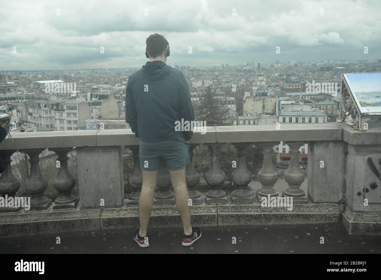 Young man with headphones looking out across Paris, pasakdek Stock Photo