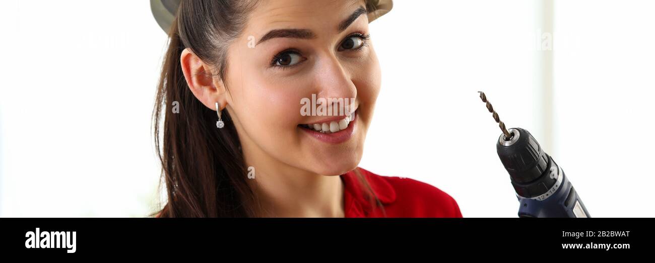 Portrait of young beautiful brunette woman holding holding hammer and drill Stock Photo