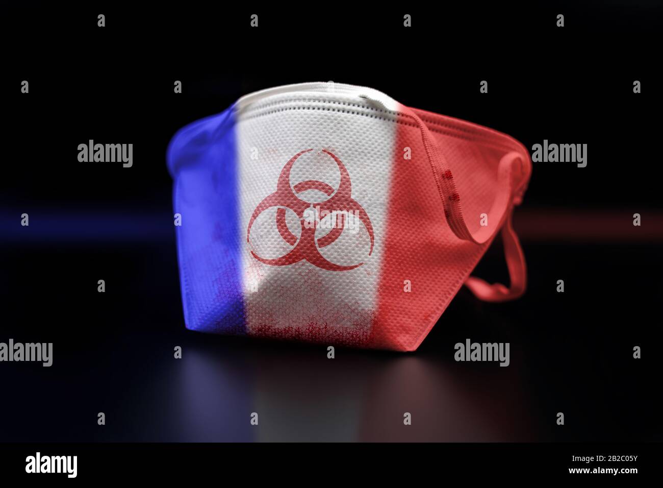 Blood-stained face mask marked with biohazard symbol to the colors of the french flag, aftermath of coronavirus COVID-19 outbreak in France. Stock Photo