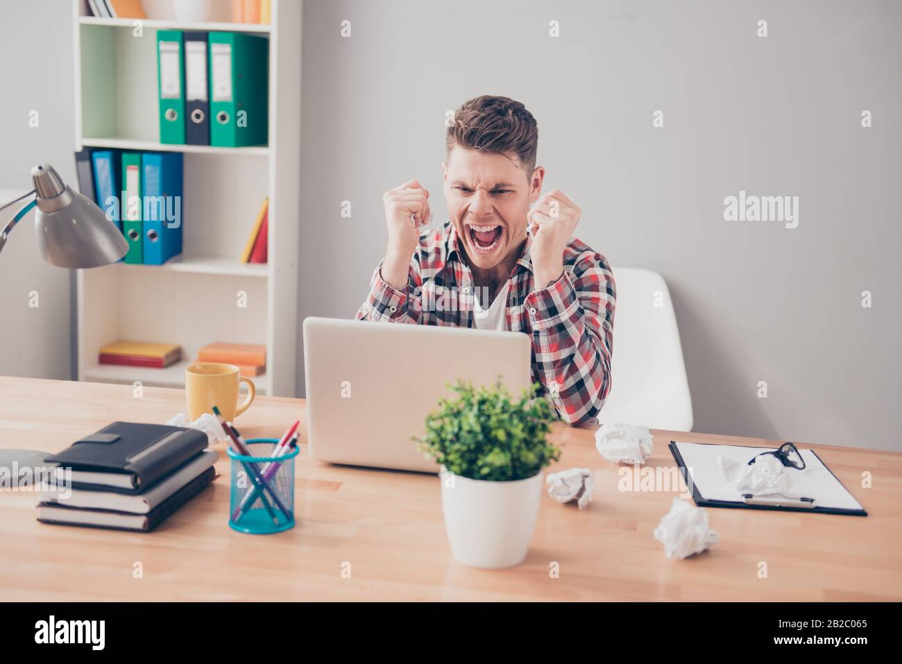 Angry furious man with laptop having a lot of work and screaming Stock Photo