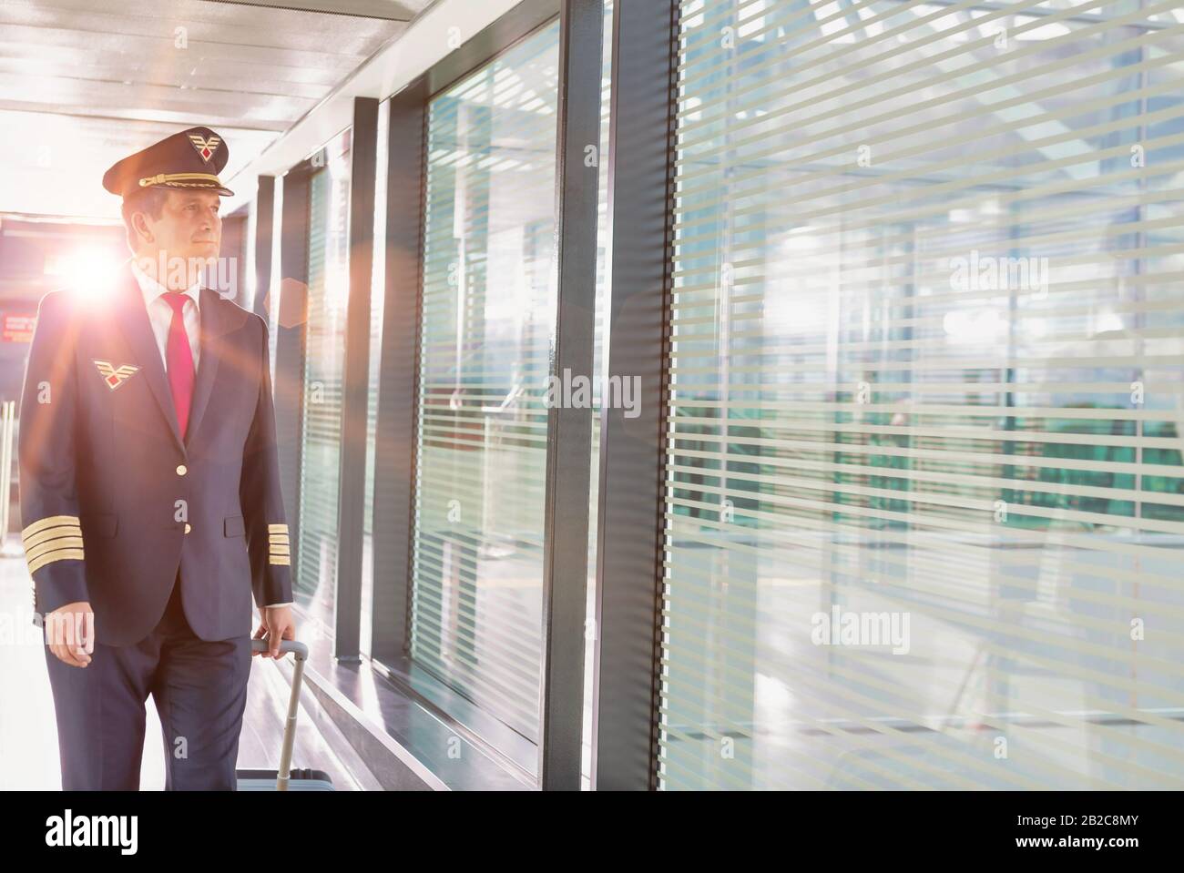 Portrait of mature pilot walking with his suitcase in airport Stock ...