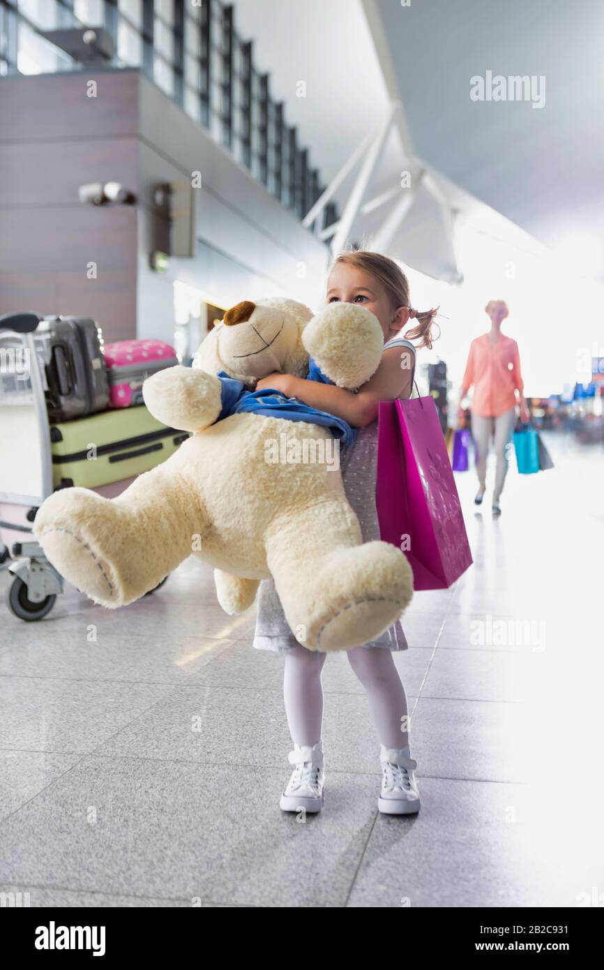 Portrait of young little girl holding her big teddy bear in airport