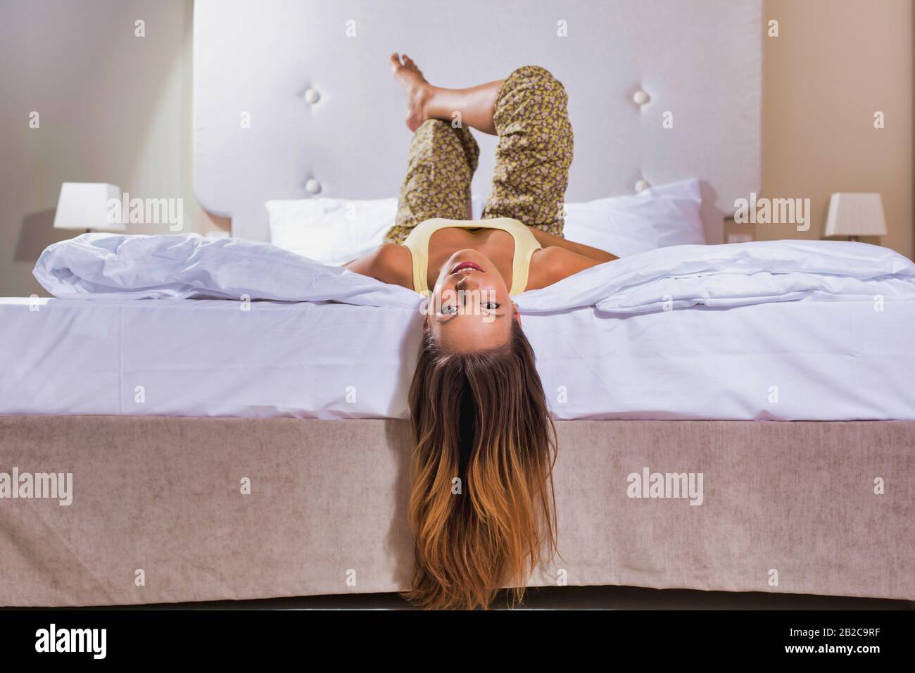 Attractive woman lying backwards off the bed letting her hair dead Stock Photo