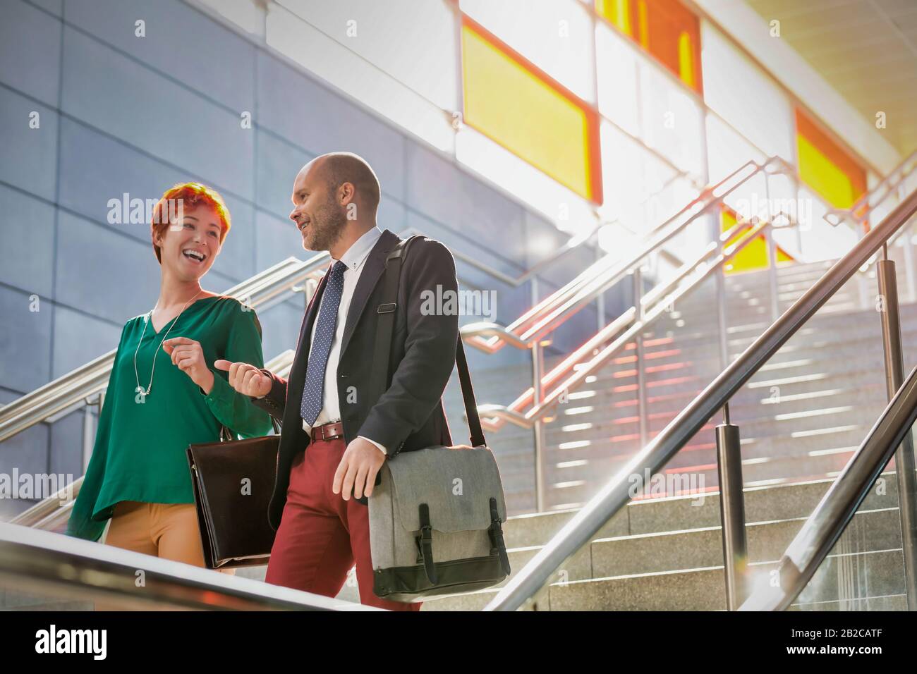 Portrait of businessman and businesswoman talking while walking down stairs Stock Photo