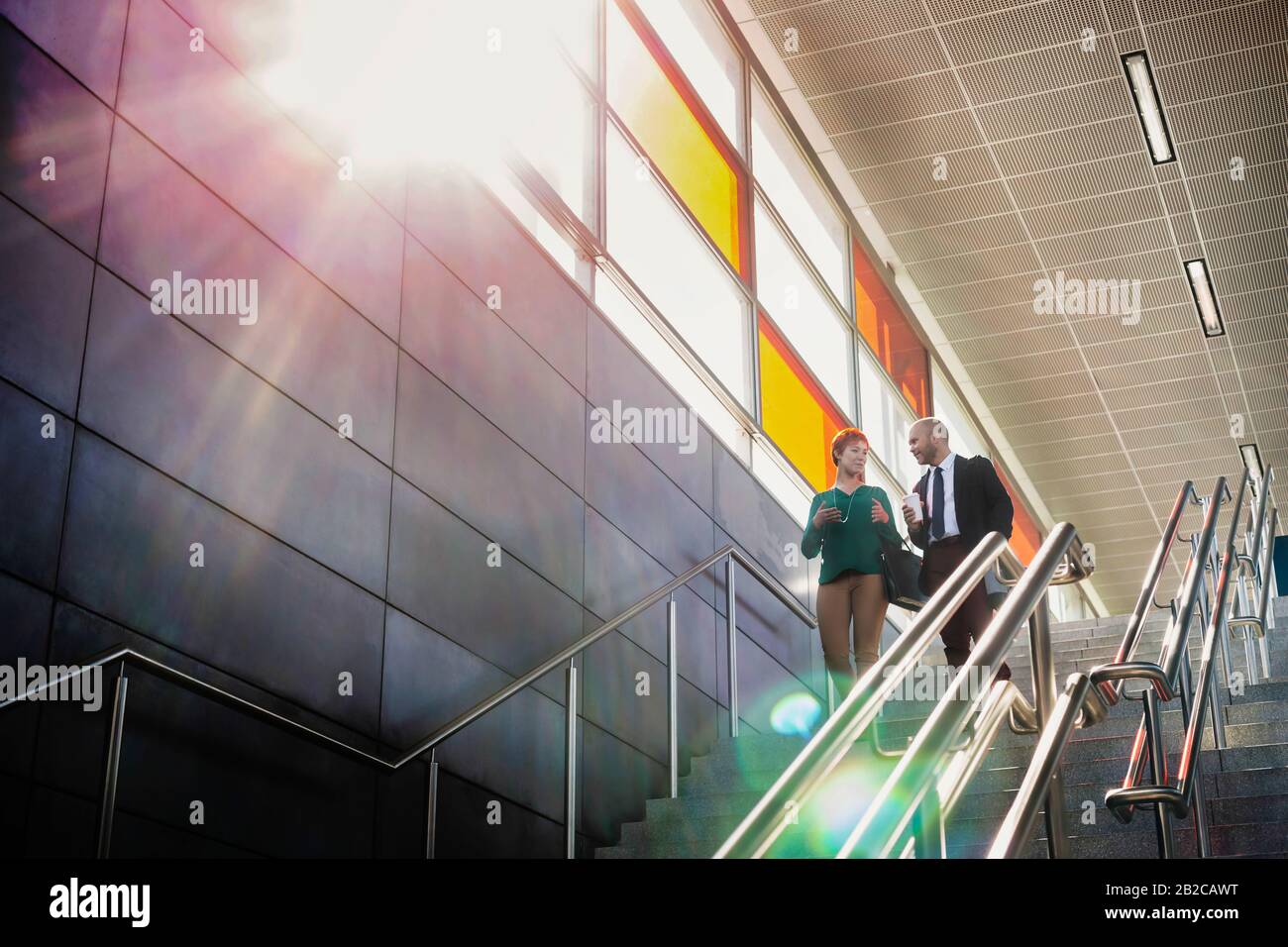 Portrait of businessman and businesswoman talking while walking down stairs Stock Photo