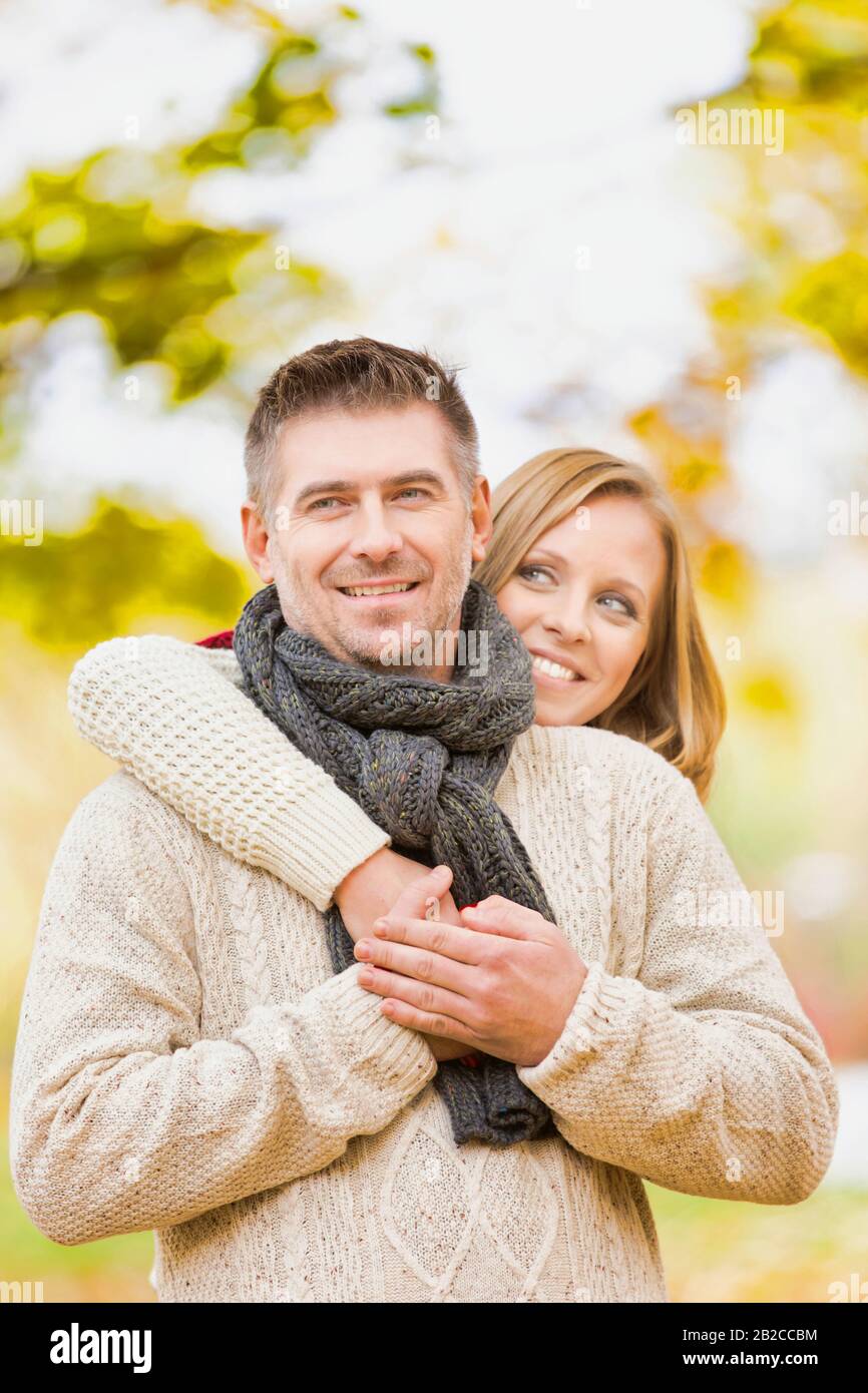 Portrait of beautiful woman hugging her husband from behind in park ...