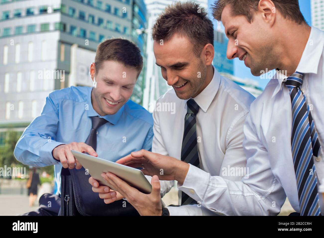 Portrait of handsome businessman showing business plan to the other businessman over digital tablet while sitting Stock Photo