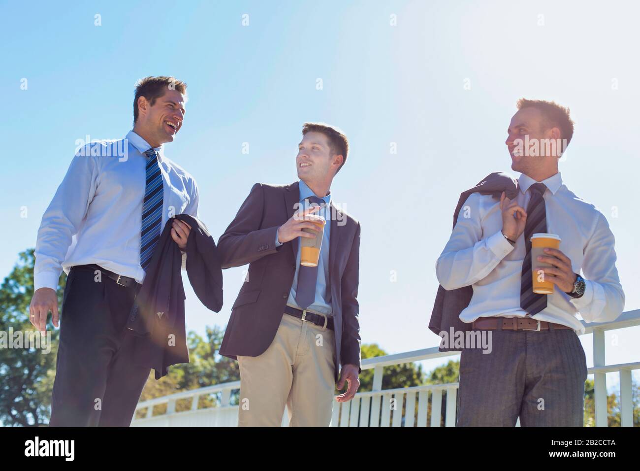 Businessmen drinking coffee while walking and talking during break Stock Photo