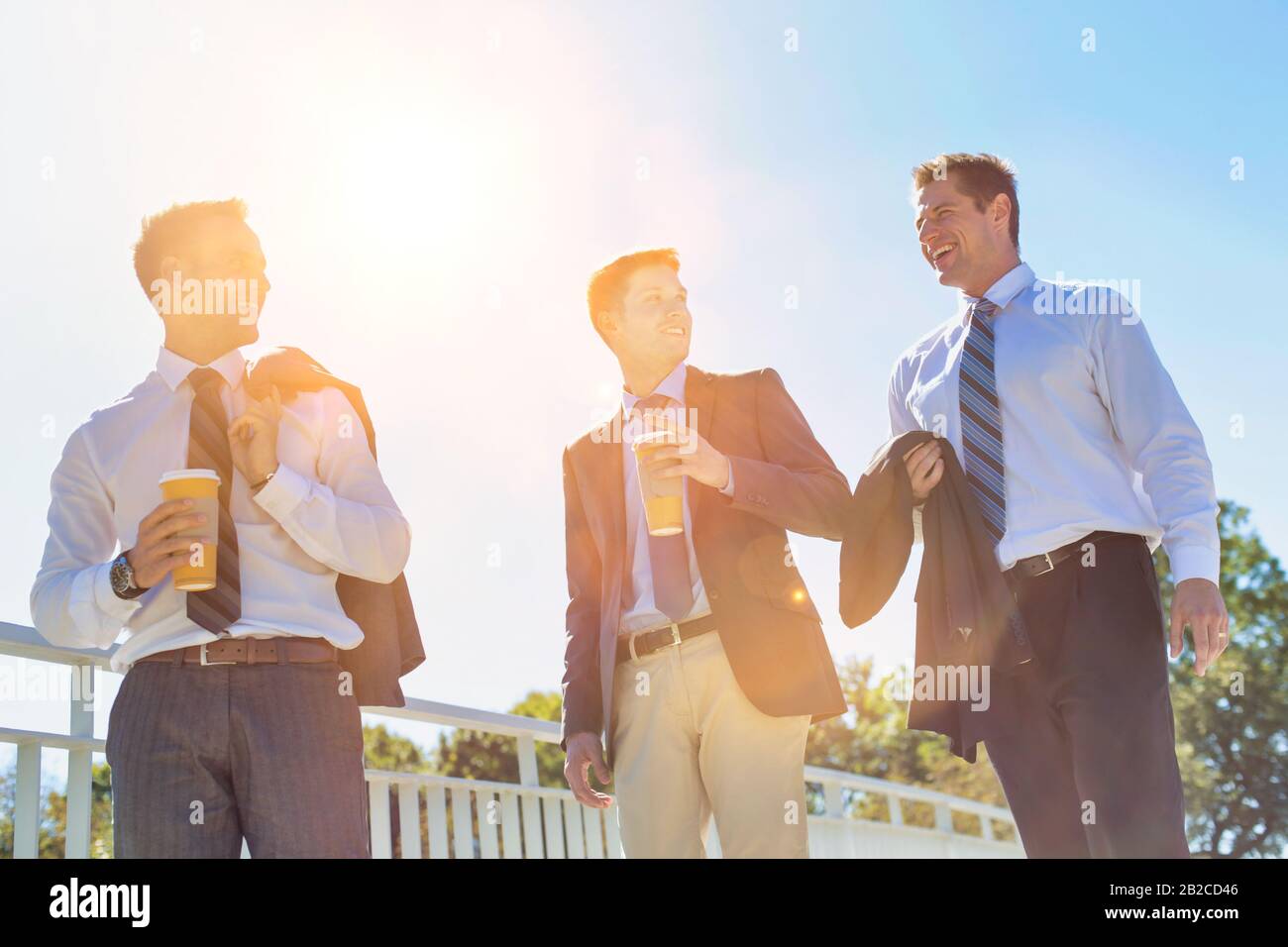 Businessmen drinking coffee while walking and talking during break Stock Photo