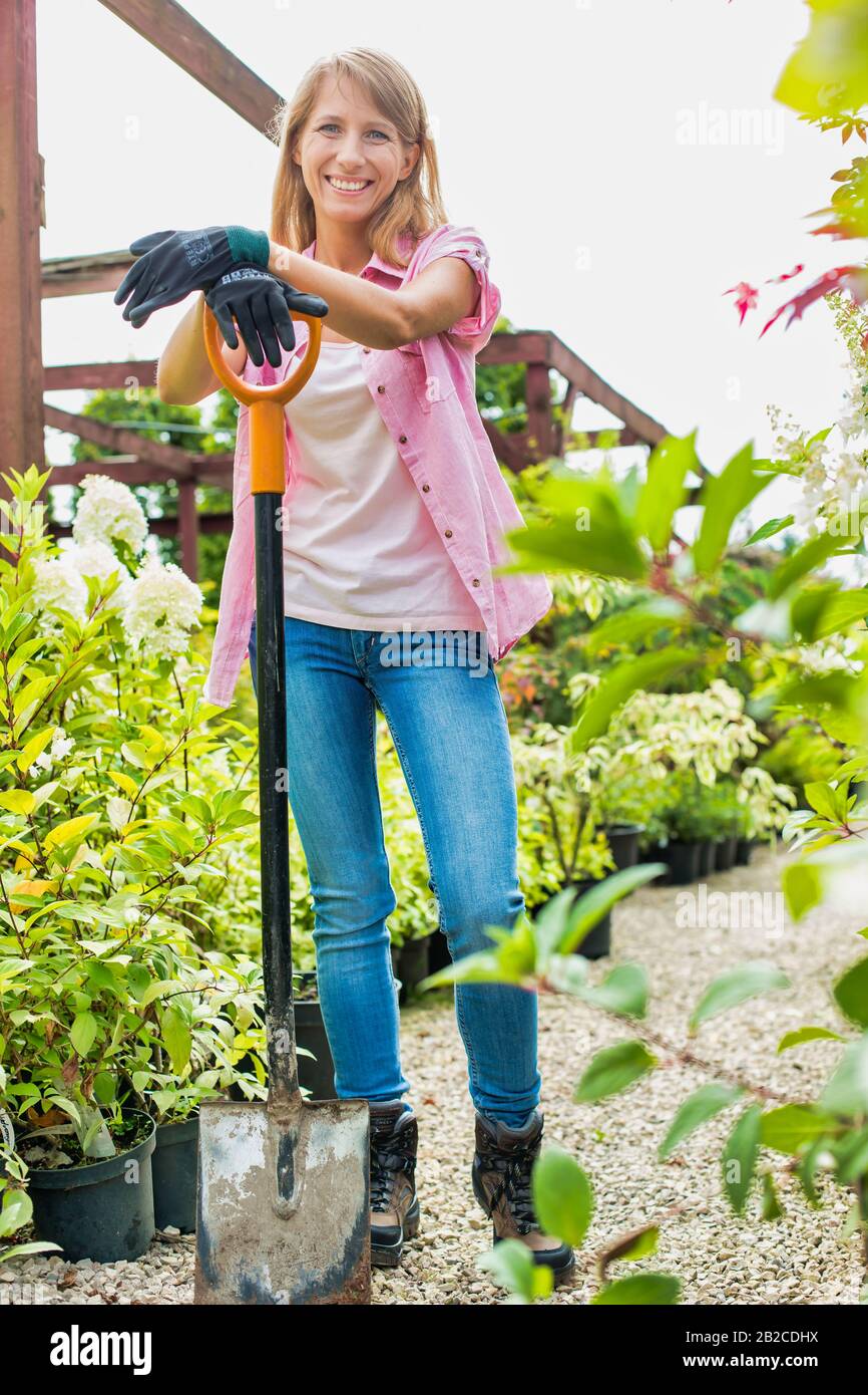 Portrait of mature gardener smiling while leaning on shovel Stock Photo ...