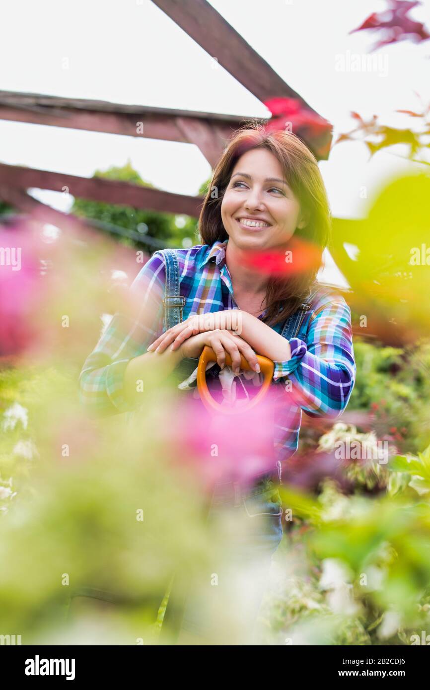 Portrait of mature gardener smiling while leaning on shovel Stock Photo ...