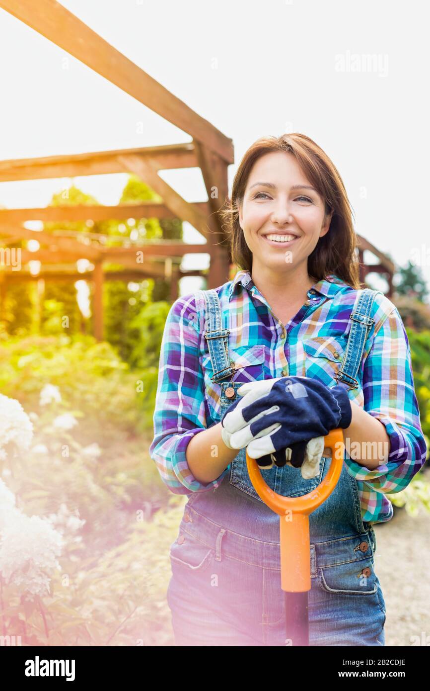 Portrait of mature gardener smiling while leaning on shovel Stock Photo ...