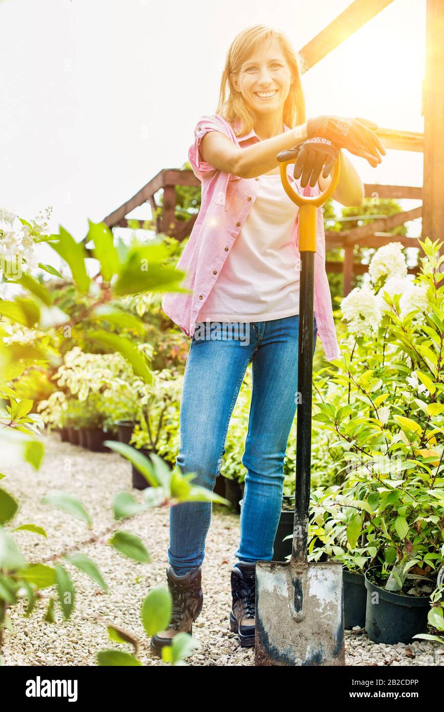 Portrait of mature female gardener holding shovel Stock Photo - Alamy