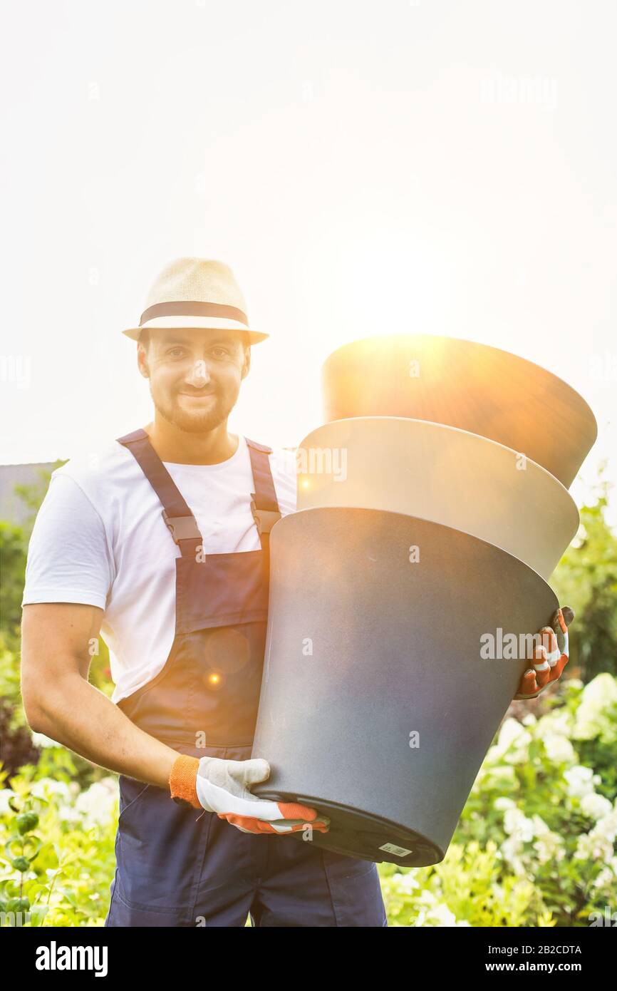 Portrait of mature male gardener carrying pots in shop Stock Photo