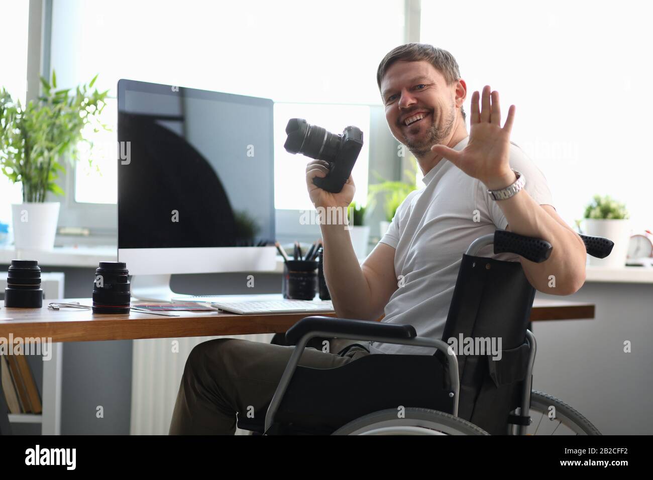 Male photographer sitting on wheelchair at table Stock Photo