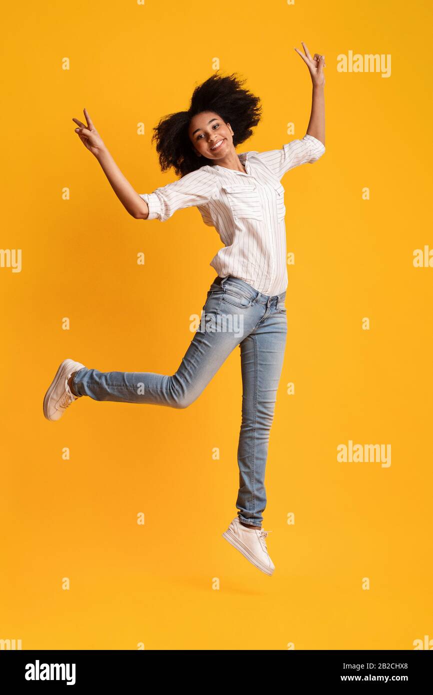 Happy Afro Girl Jumping In The Air And Gesturing Peace Sign Stock Photo ...