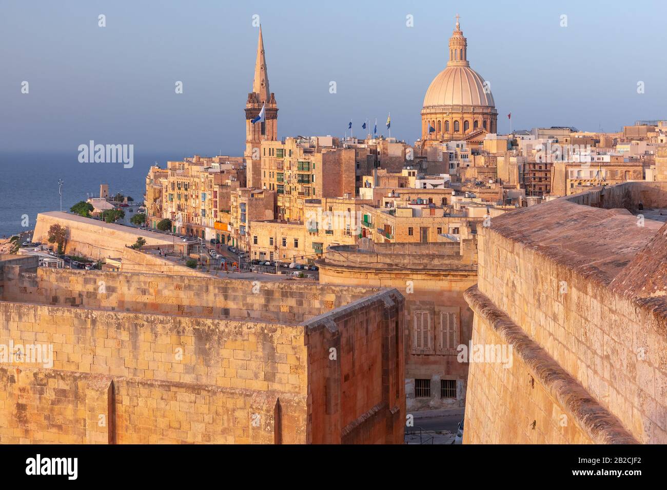 View of Old town roofs, fortress, Our Lady of Mount Carmel church and St. Paul's Anglican Pro-Cathedral at sunset , Valletta, Capital city of Malta Stock Photo