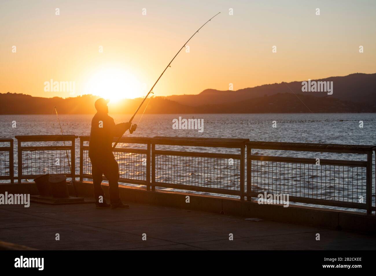 A man casts a fishing line into the water at Point Richmond, CA, during