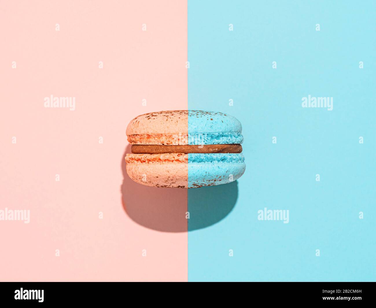 Creative layout with macaron. Trendy light. Two colors macaron or macaroon on duotone coral pink and blue background. Top view or flat lay. Hard light Stock Photo