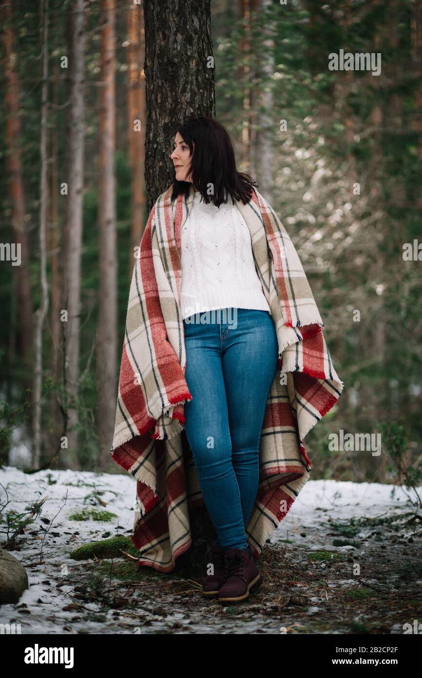 Young girl covered with blanket in forest. Portrait of a woman covered