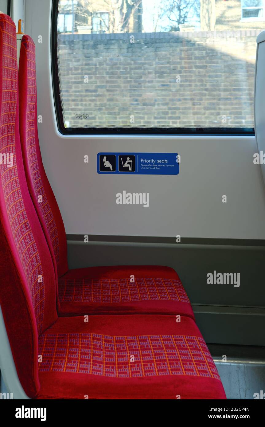 Close up of an empty train seat with a  sign indicating 'Priority seats for elderly people and anybody who might need them',London England UK Stock Photo