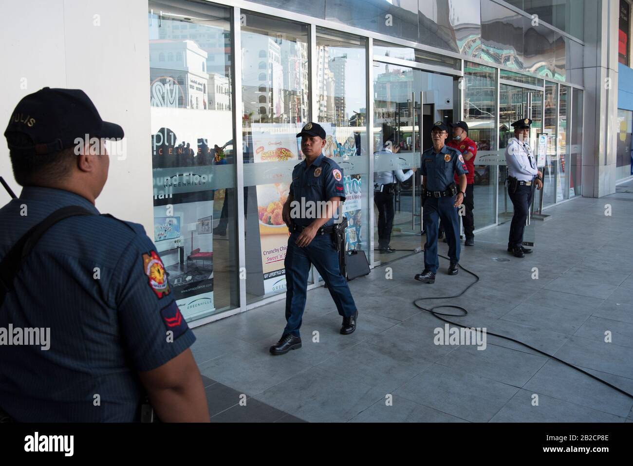 Police officers stand alert outside V shopping Mall in Manila.Police