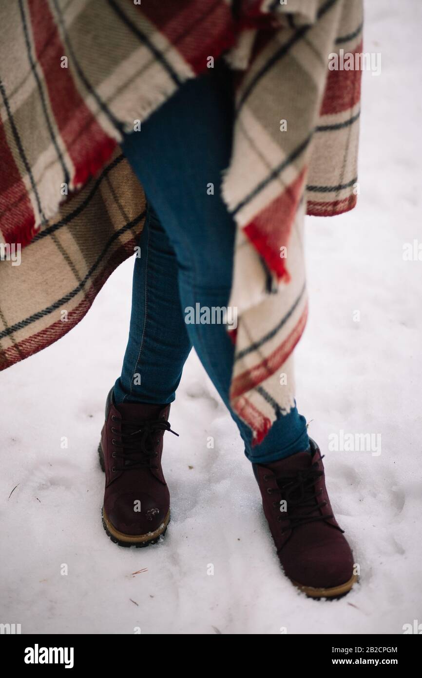 Crossed female legs in jeans on snow. Close up view of female legs