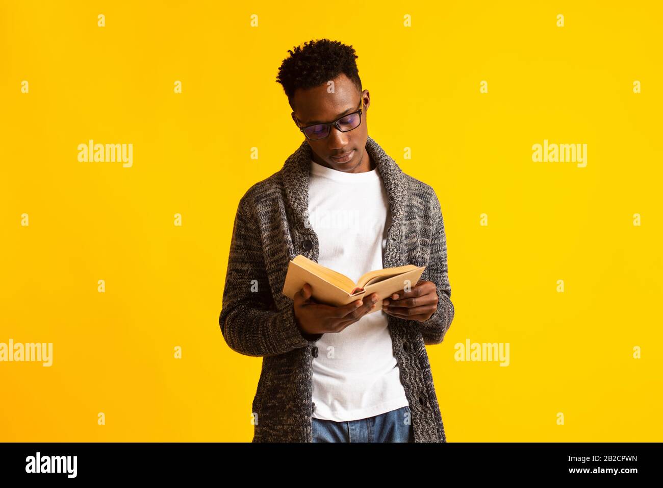 Concentrated young african guy on yellow background Stock Photo