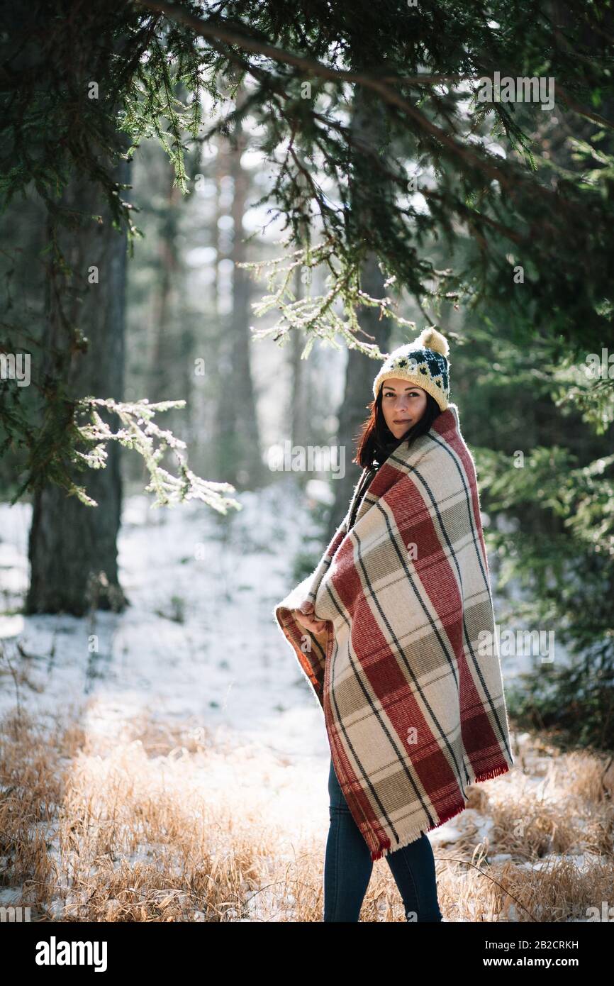Beautiful woman covered with blanket in park with snow. Pretty girl