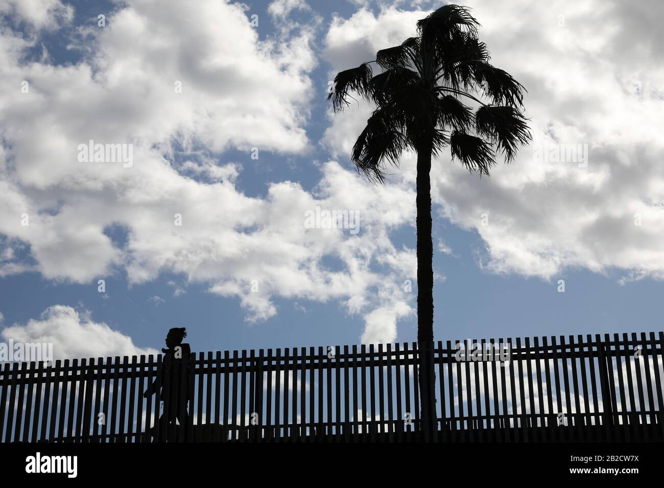 One person walks on a bridge in the city of Valencia, crossing the Turia park, in a cloudy day. Stock Photo