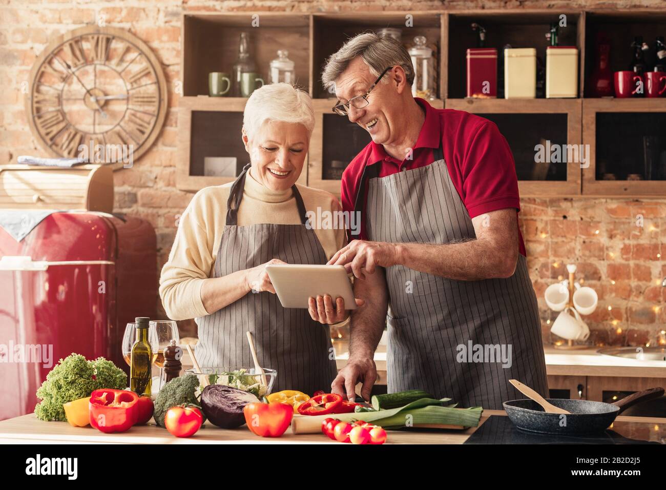 Elderly couple using digital tablet in kitchen, looking for new recipes Stock Photo