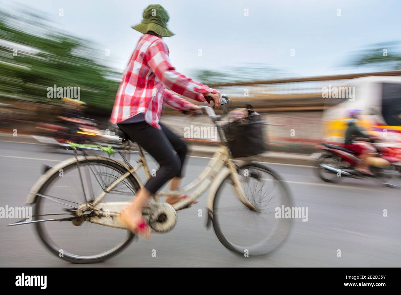 Motion blurred photograph of a Vietnamese woman on a bicycle Stock Photo