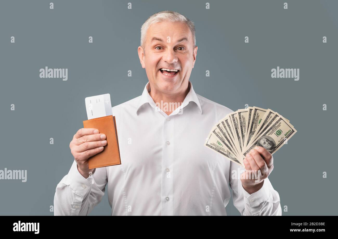 Excited man holding tickets and passport at grey studio Stock Photo
