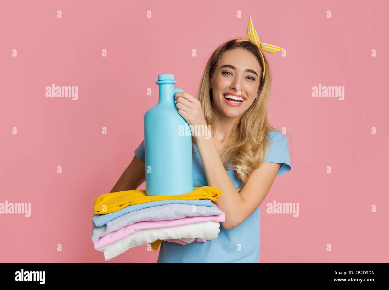 Smiling girl holds clean clothes and fabric softener Stock Photo Alamy