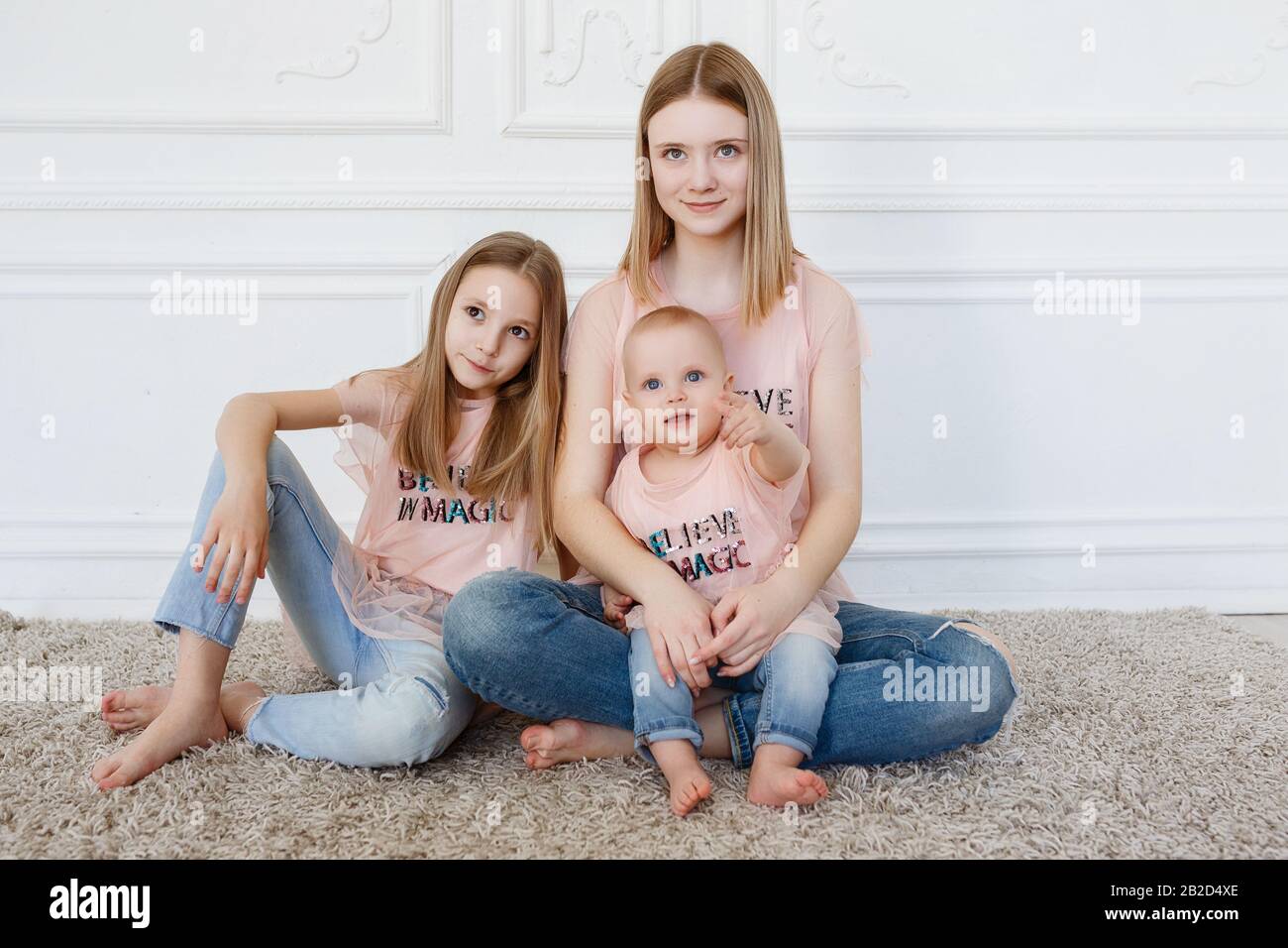 Light family series. Three sisters on a white background, dressed in funny  t-shirts and jeans Stock Photo - Alamy