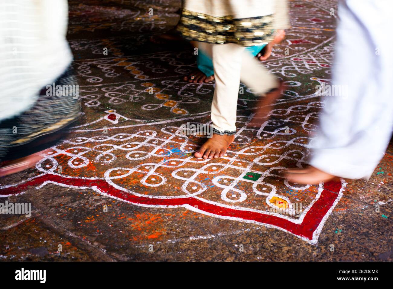 Abstract image of motion blurred barefoot pilgrim people in colorful clothes walking on the floor with painted mandala ornament. Traditional decoratio Stock Photo