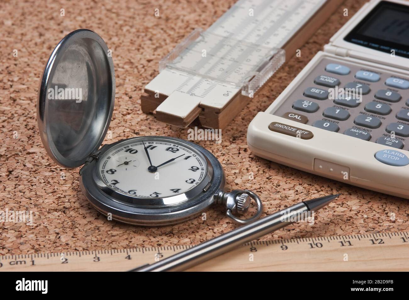 pocket watch, calculator and slide rule on a cork board Stock Photo - Alamy