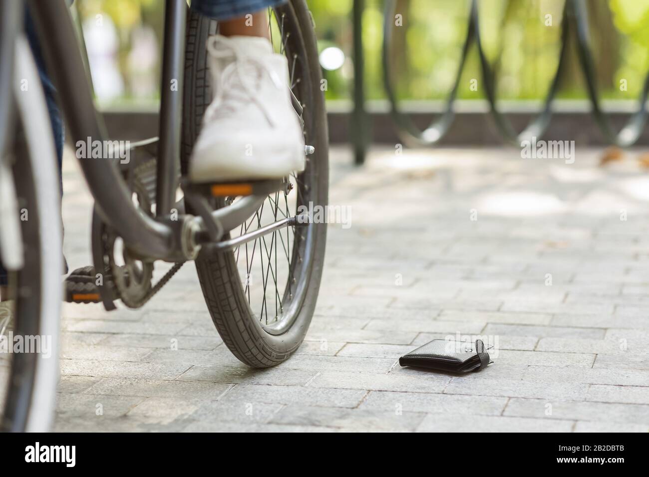 Money Lost. Unrecognizable Black Man Dropped His Wallet While Riding Bicycle Stock Photo
