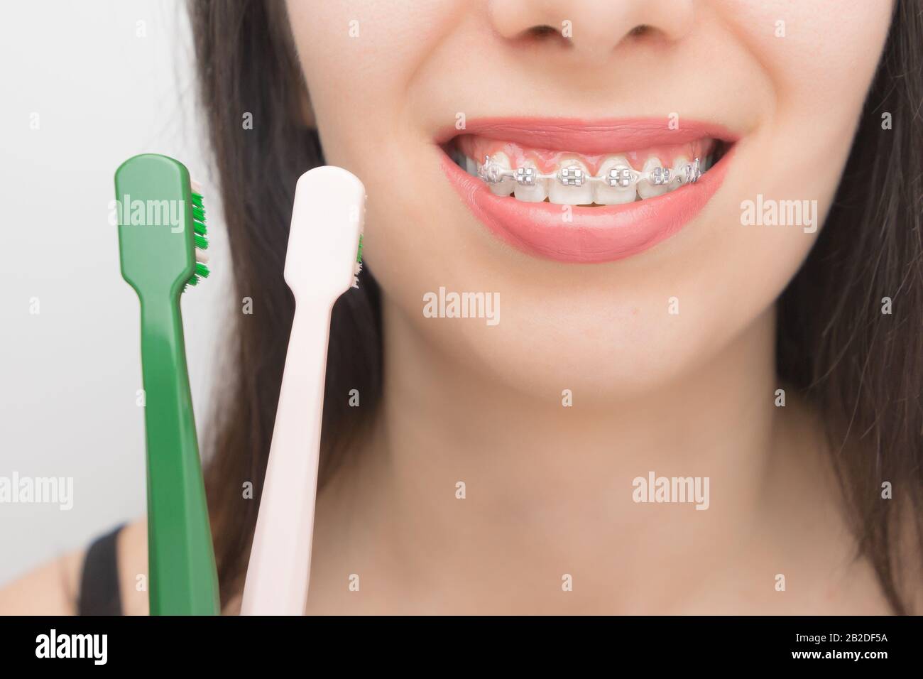 Cleaning teeth with dental braces by brushes. Happy woman with brackets