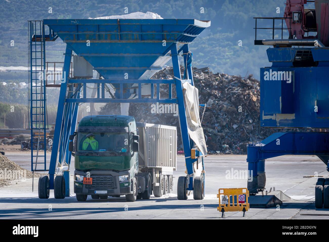 Truck in the port loading fertilizer that unloads a crane from the ship Stock Photo