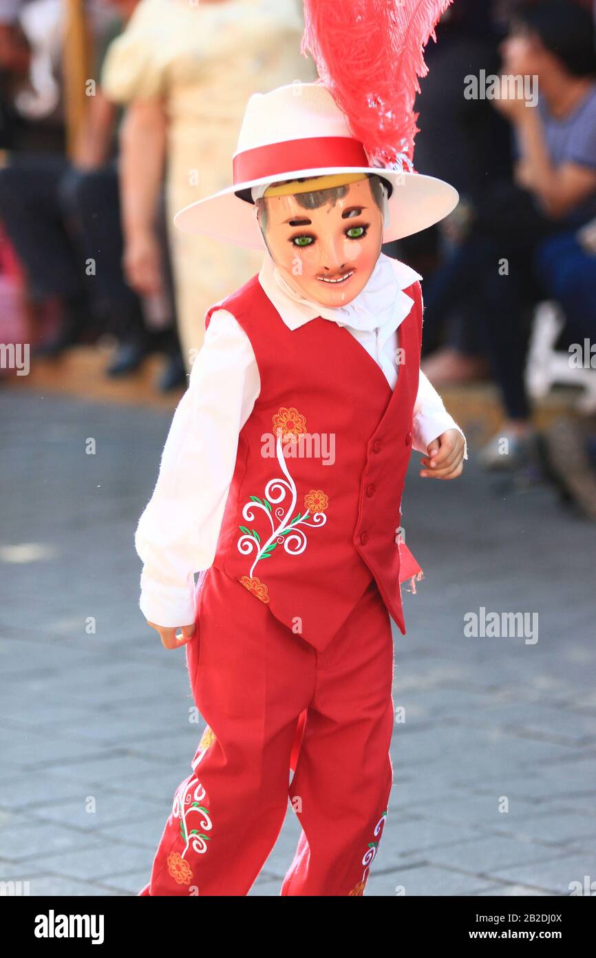a small boy dances folk mexican huehue dance with red costume and wood