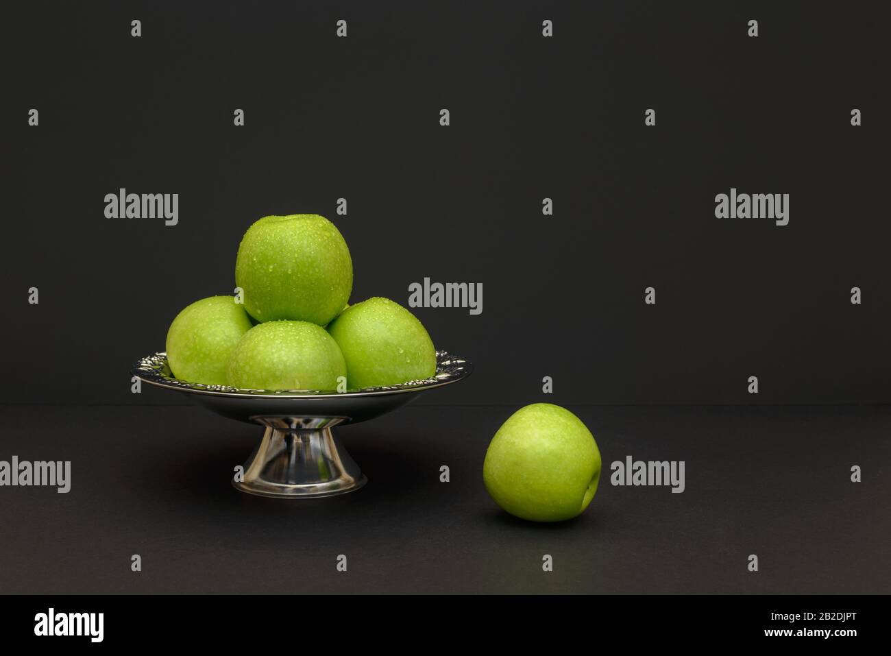Fresh green apples in antique silver bowl on a black background Stock Photo